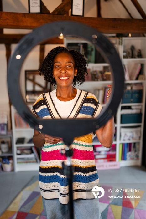 Smiling woman standing in front of ring light at home