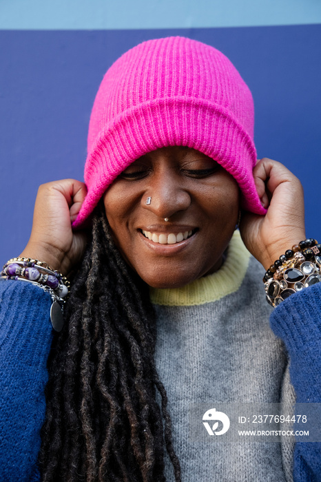 Portrait of beautiful woman putting on pink cap