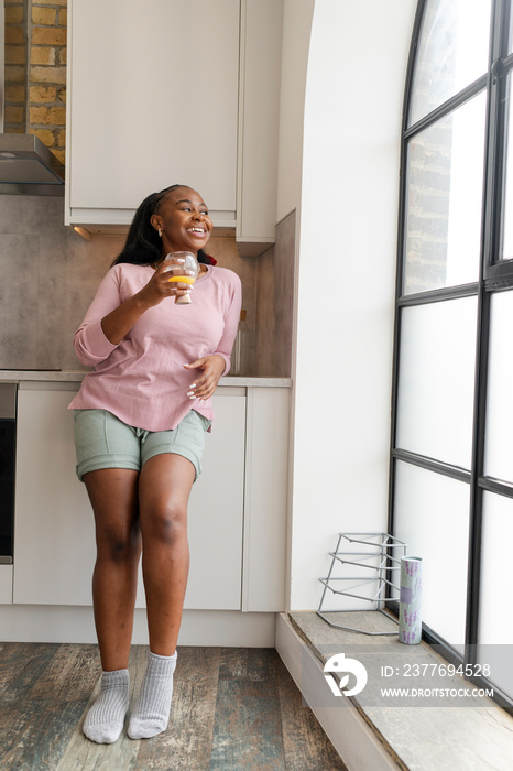 Smiling woman standing and looking through kitchen window