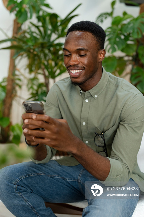 Young man with smartphone sitting in office lounge