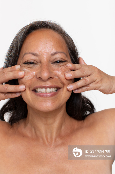 Studio portrait of smiling woman applying face cream