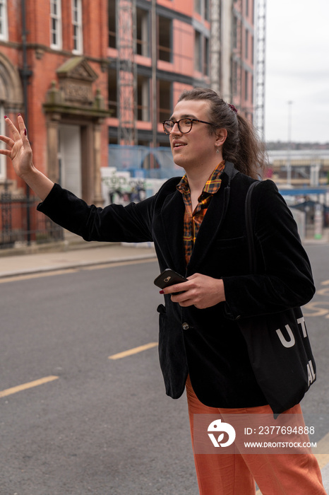 Young man waving to stop bus on city street