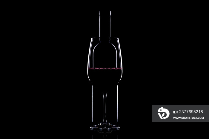 Elegant red wine glass and a wine bottle over black background