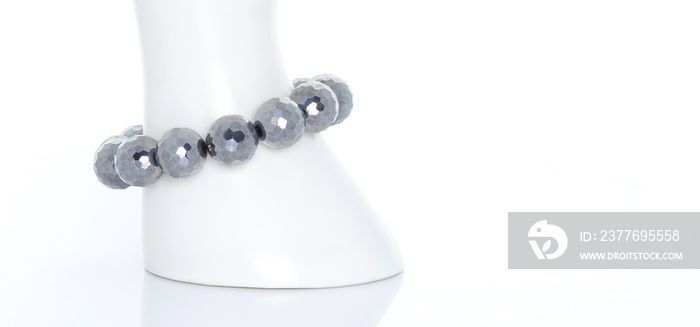 Terahertz bracelet on a white display stand. Terahertz stone can increase blood circulation and stimulate metabolism and rejuvenation. Collection of natural gemstones accessories. Studio shot