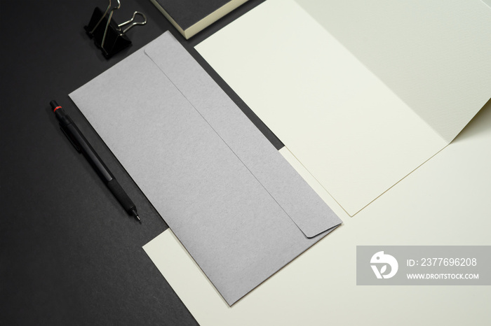 Stationery branding mockup template with red A4 Letterhead, business card, envelope, note bookpencil.  Dark background real photography.