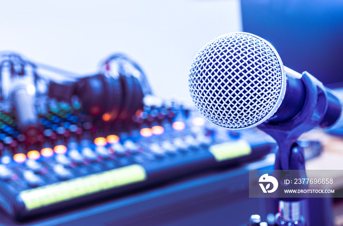 Microphone on tripod with mixer background in sound control room.