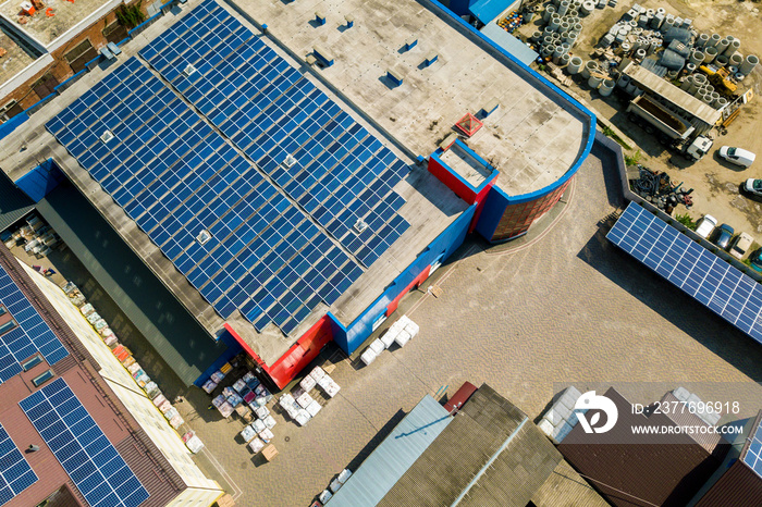 Aerial view of many photo voltaic solar panels mounted of industrial building roof.