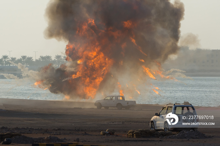 Military strike or bomb in war causes fire ball and explosion amid  cars and town in chaos. Military war concept. Strength, power, force, fire, explosion.