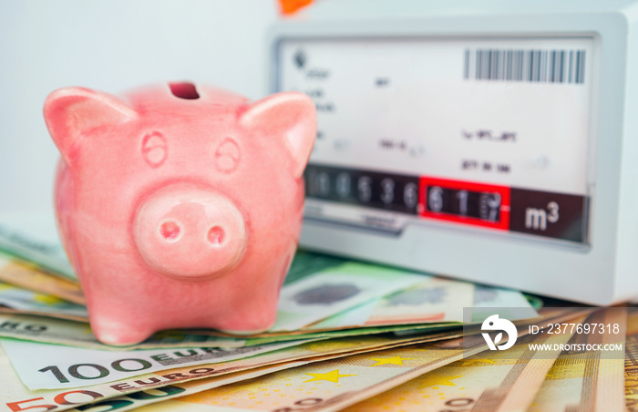 Piggy bank near a natural gas meter at home. The symbolic image of the high cost of natural gas for heating homes in the winter time, energy efficiency.