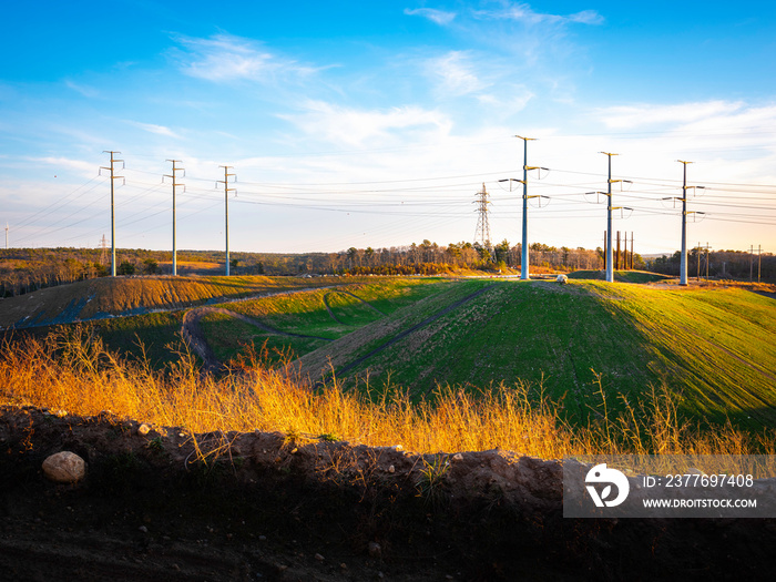 Industrial Landscape with Electricity Pylons on the Hills. Dramatic Cloudscape over Electric Poles and Cables on Blue Sky. Retro Technology Backdrop Image with Space for Text or Design