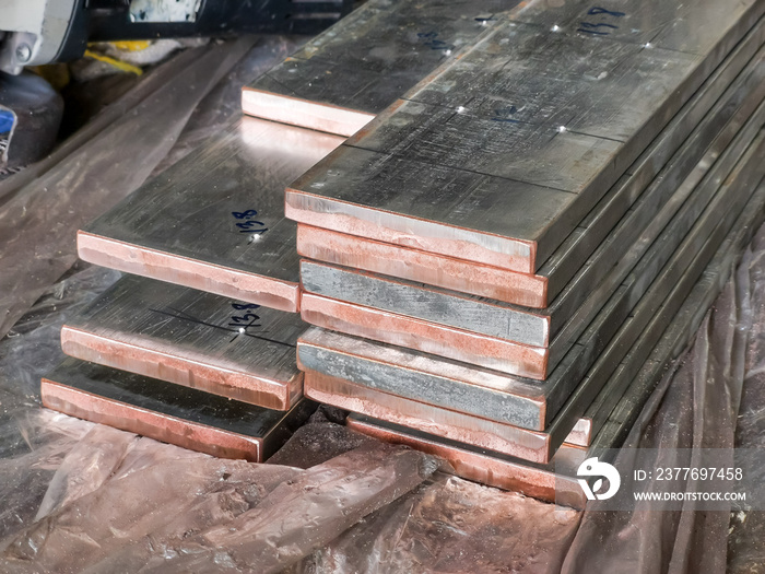 Fresh cut tinted copper busbar stacked on the table.