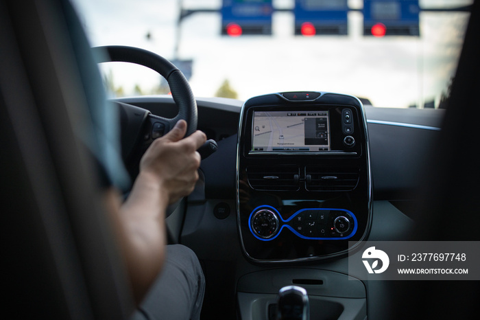 Young man driving an electric vehicle in a city context. Car sharing concept. eCar concept.