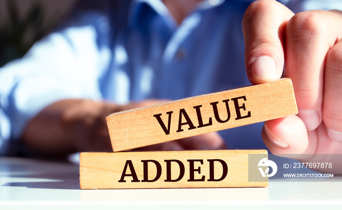 Close up on businessman holding a wooden block with Value added message, business concept