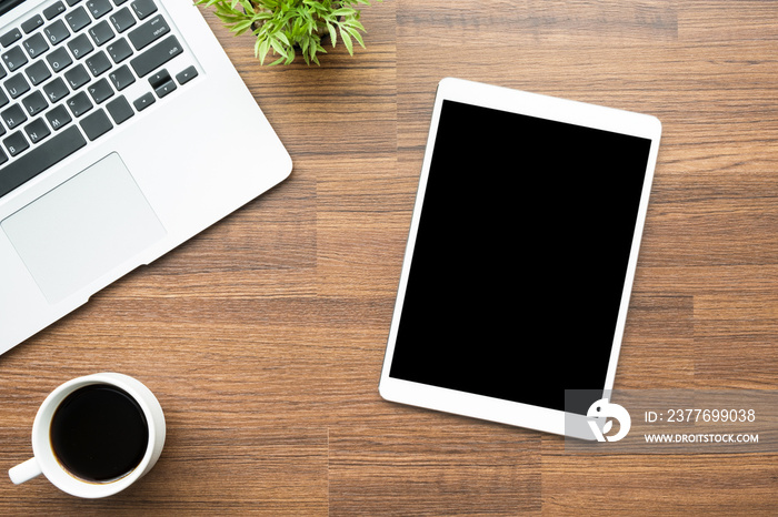 Wood office desk table with tablet with blank screen, laptop and cup of coffee. Top view, flat lay.