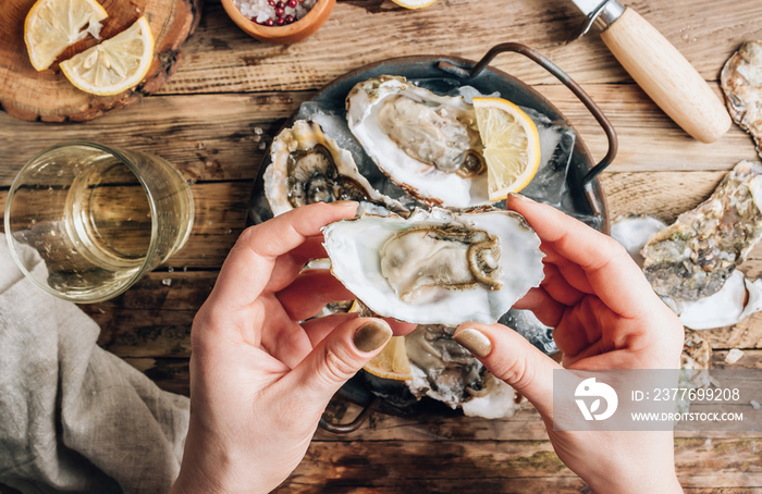 Fresh oysters with ice and lemon on a rustic wooden background.