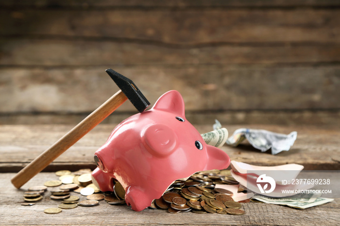 Broken piggy bank with cash and coins on wooden background