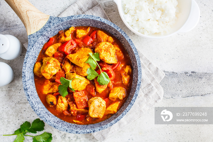 Jalfrezi chicken in fried pan with a bowl of rice, top view, copy space. Traditional indian cuisine concept.