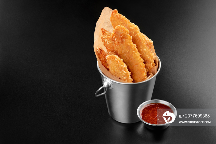 BBQ Chicken fried stripes in a metal bucket onblack background with sauce food