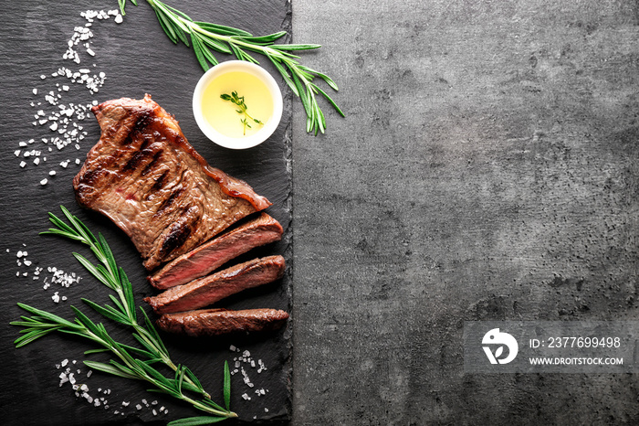 Slate plate with tasty steak, herbs, oil and salt on grey background