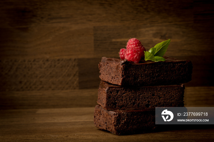 Brownies, delicious stacked brownies with raspberries isolated on wooden background, copy space