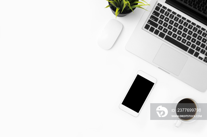 White office desk table with laptop computer, smartphone with blank screen, and supplies. Top view with copy space, flat lay.