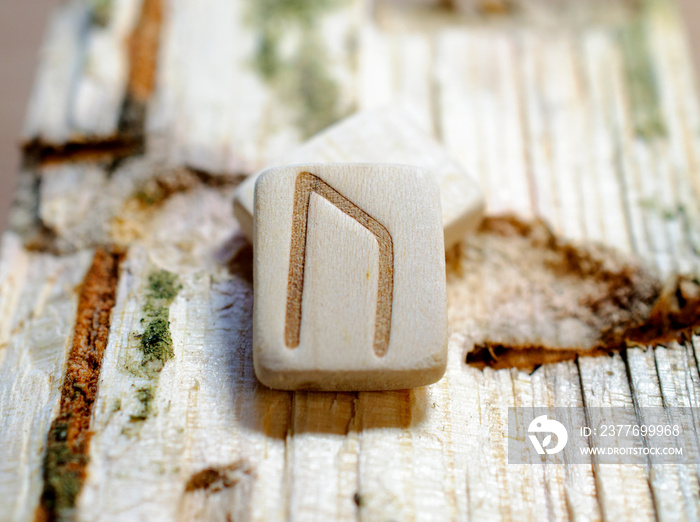 Wooden rune Uruz close-up on a wooden background. Soft focus