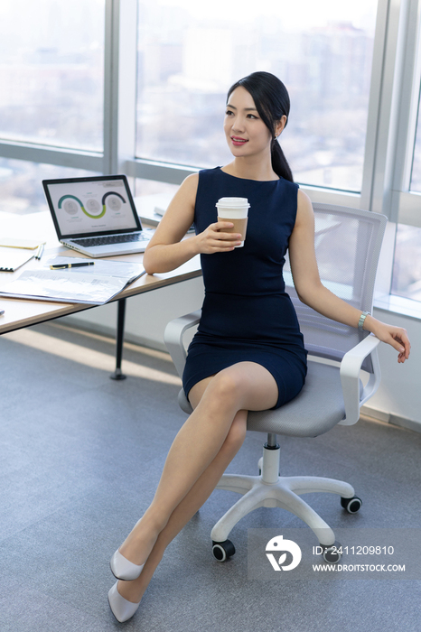 年轻商务女士在办公室喝咖啡