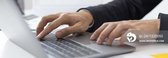 Young Asian office worker presses he finger on a laptop keyboard to analyze financial data and summarize her work in a private office, Office workers, handsome male employee in a black suit.