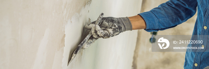 master is applying white putty on a wall and smearing by putty knife in a room of renovating house in daytime BANNER, long format