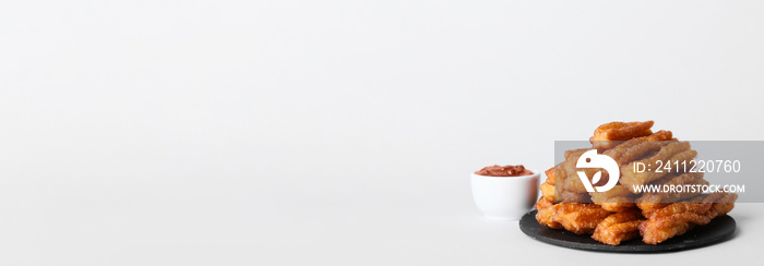 Slate plate with tasty churros and chocolate sauce in bowl on light background with space for text