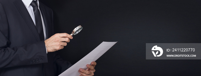 suit man examines document with magnifying glass