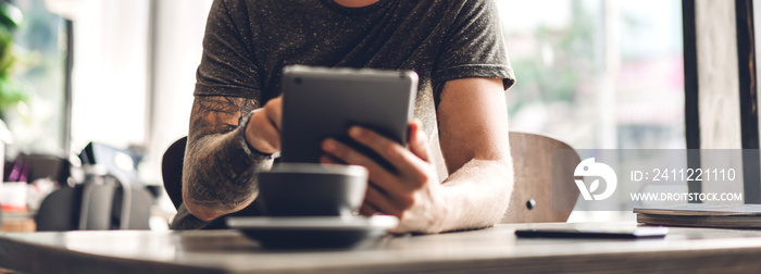 Hipster man relaxing using digital tablet computer and looking at screen relaxing with device work study while sitting on chair in cafe and restaurant.technology and communication concept