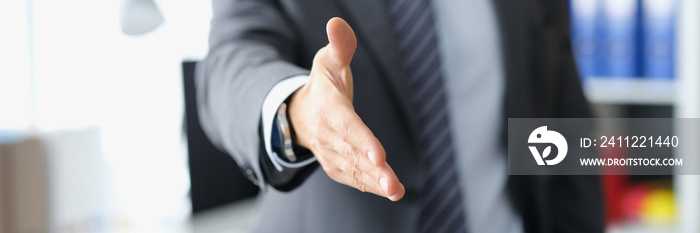 Man in business suit stretches out hand for handshake