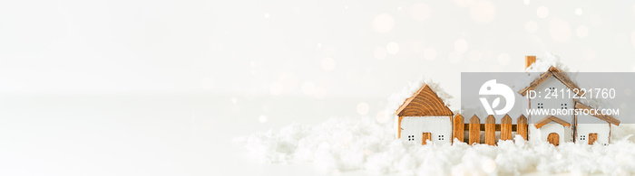 Happy New Year and Merry Christmas banner. Festive white background with toy wooden house, snow, light bokeh, christmas tree, village and decoration. Copy space for winter holidays greeting card.