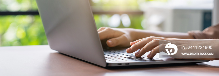 Hand using computer laptop and touching mouse on the table.