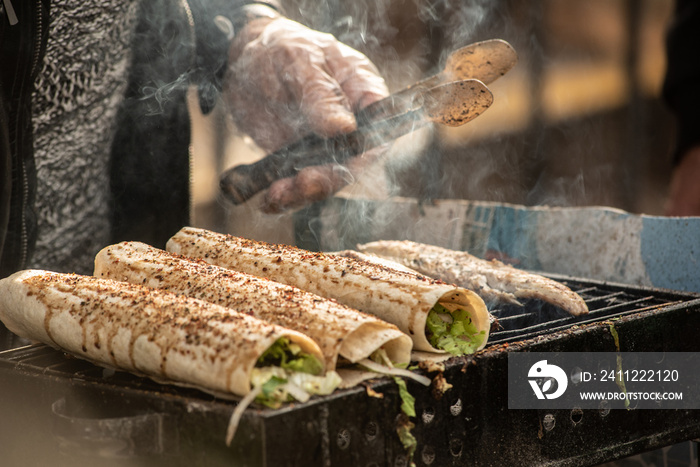 Tasty Turkish street food, grilled fish wrap sandwiches cooking on a stall outside in Karakoy, Istanbul, Turkey.