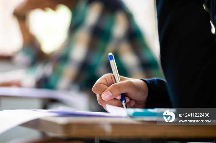 Close up Students writing and reading exam answer sheets exercises in classroom of school with stress.