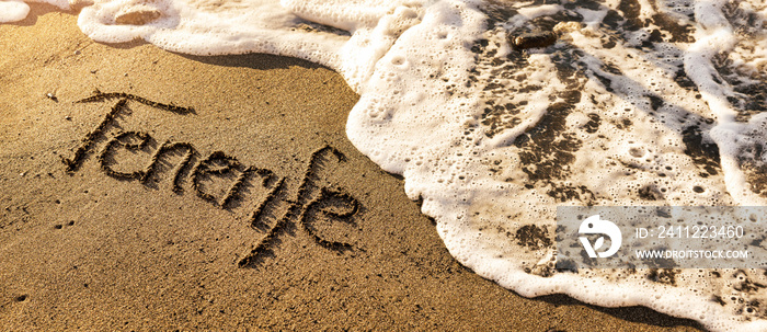 tenerife vacations - text and ocean wave on beach sand. banner copy space