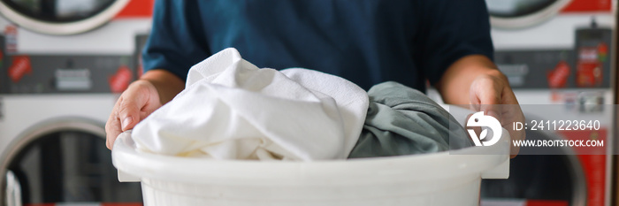 Man doing launder holding basket with dirty laundry of the washing machine in the public store. laundry clothes concept