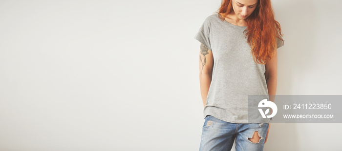 Young girl wearing grey blank t-shirt and blue jeans. Concrete wall background with copy space for your text message or promotional content