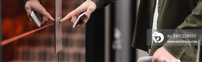 cropped view of man holding mobile phone and pressing call button of elevator in hotel, banner.