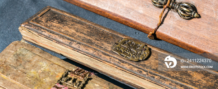 closeup of old Tibetan narrow praying books with bronze decorations