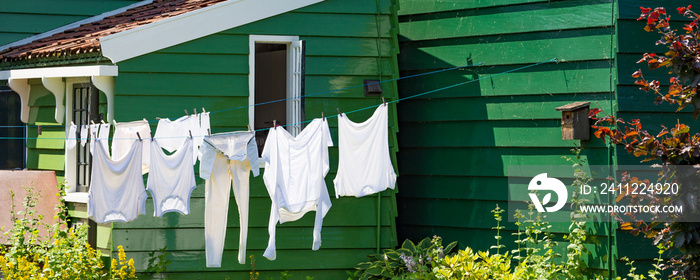 Typical example of Dutch culture. white laundry hanging outside in front of wooden green house in The Netherlands