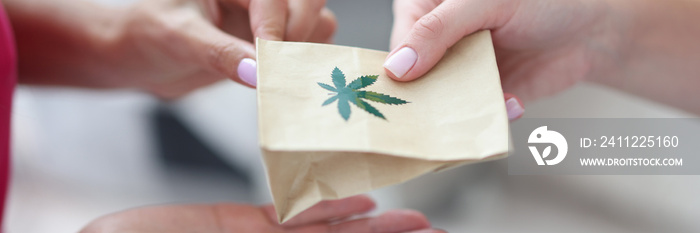 Handing over paper bag with marijuana sign.