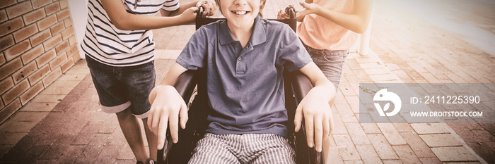 School kids pushing a boy on wheelchair