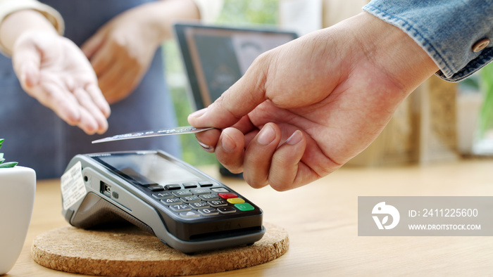 Close-up hand asia woman people work in small sme coffee cafe shop store owner use cashless wifi paywave nfc scan app smart pos reader sale in take out food drink order in urban city life contactless.