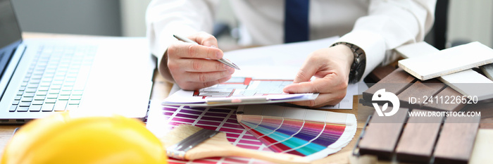 Designer in office sits at table with project and a color palette for the interior. Planner apartment houses offices concept