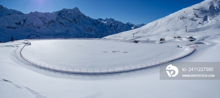 Passo del Tonale, Italy. Artificial water catchment reservoir for snow skiing slopes. Winter time. Frozen lake