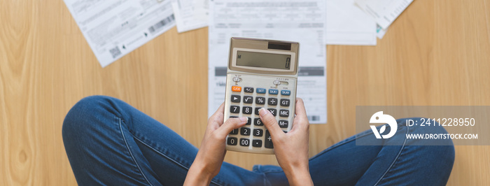 Stress asian young employee, businesswoman hand press on calculator to calculate budget, cost income, expenses of credit card for payment sitting on floor at home. Financial, finance people concept.