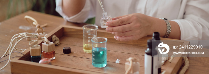 Close-up of a pipette with oil and a glass bottle. woman pouring perfume in bottle. Perfume creating workshop